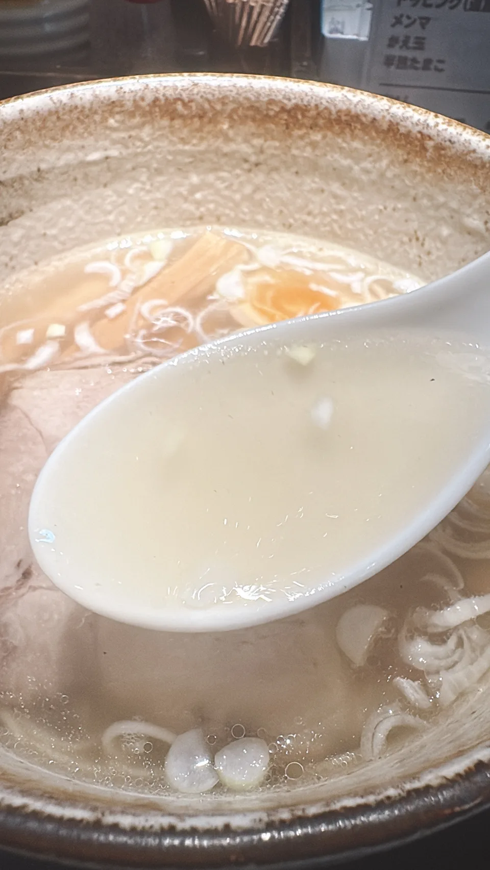 草津亭の塩ラーメンのスープをレンゲですくったところ