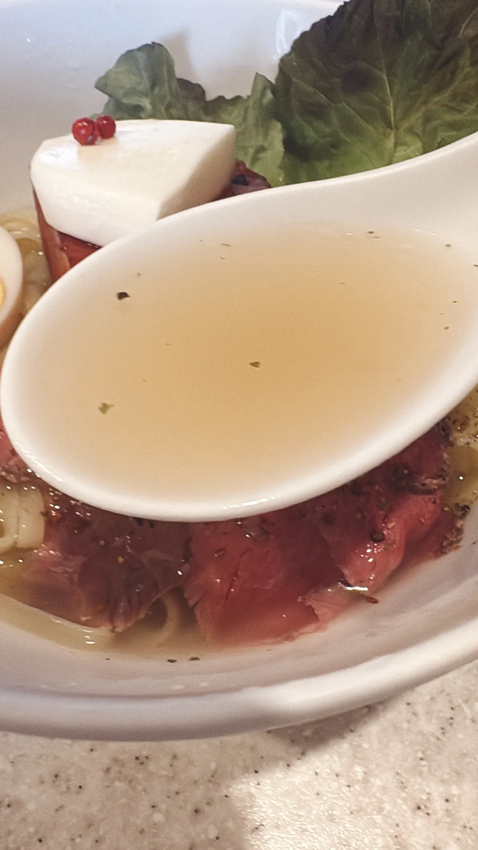ありがた屋の洋風冷やし牛香露のスープをレンゲですくったところ