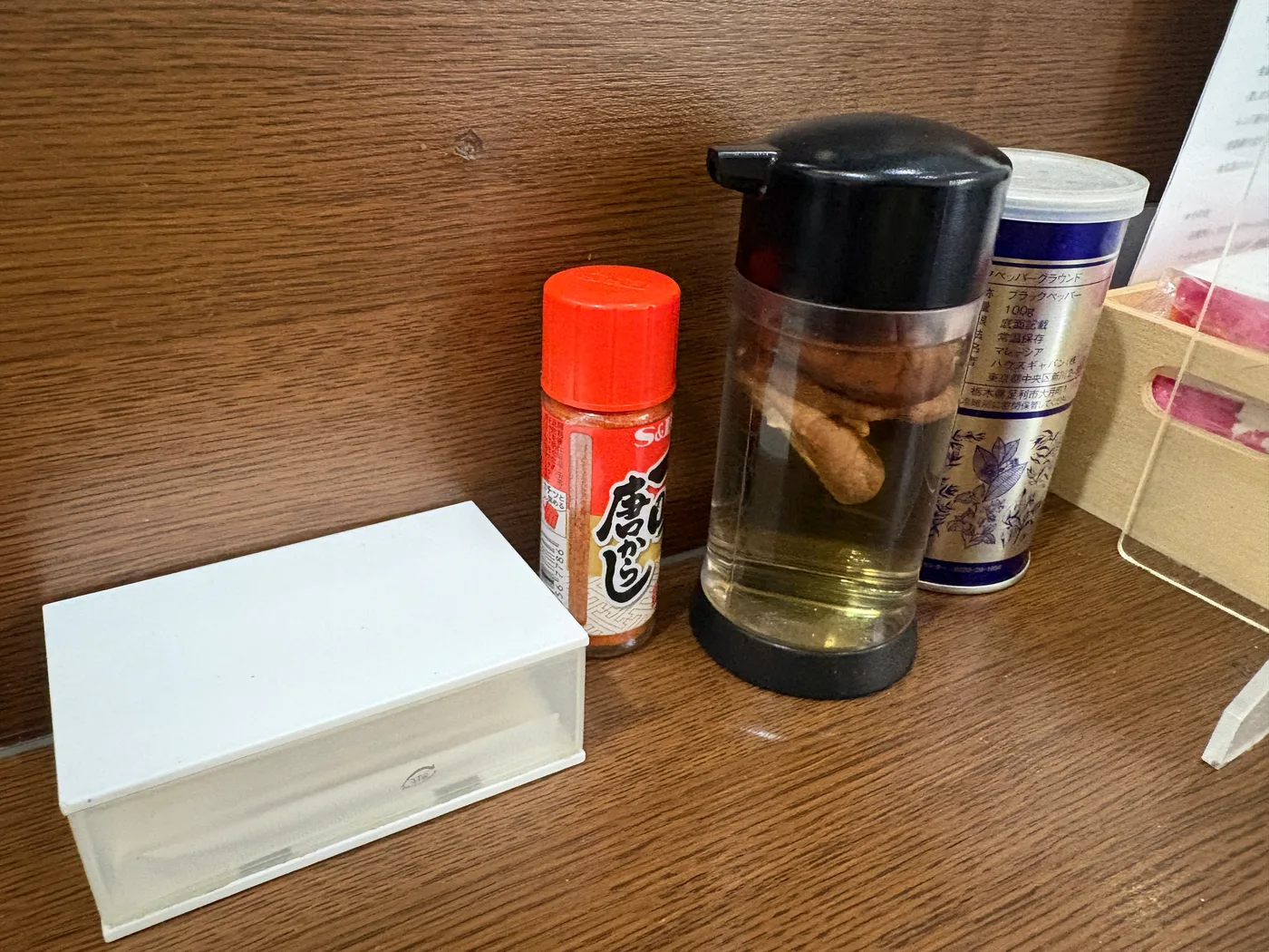 魚魚の卓上調味料。一味唐辛子、黒胡椒、香味油などが並ぶ