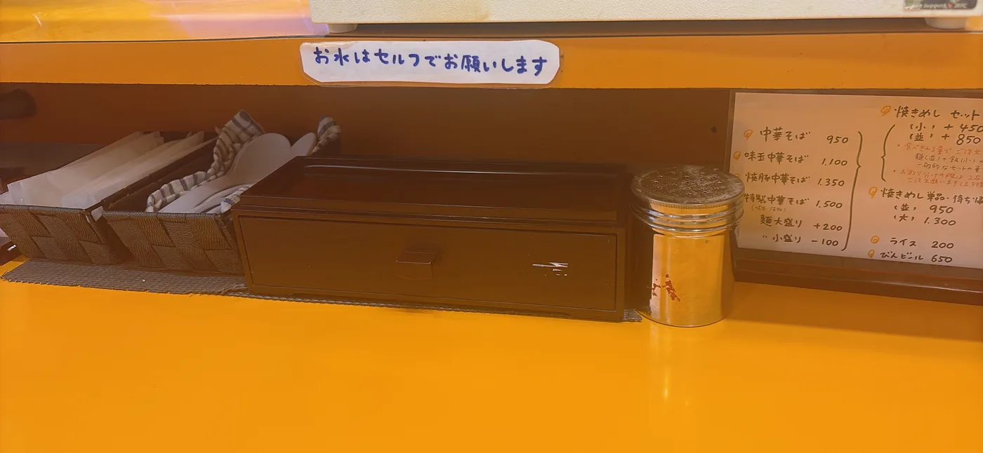 太陽食堂の卓上調味料。お水はセルフでとの案内あり