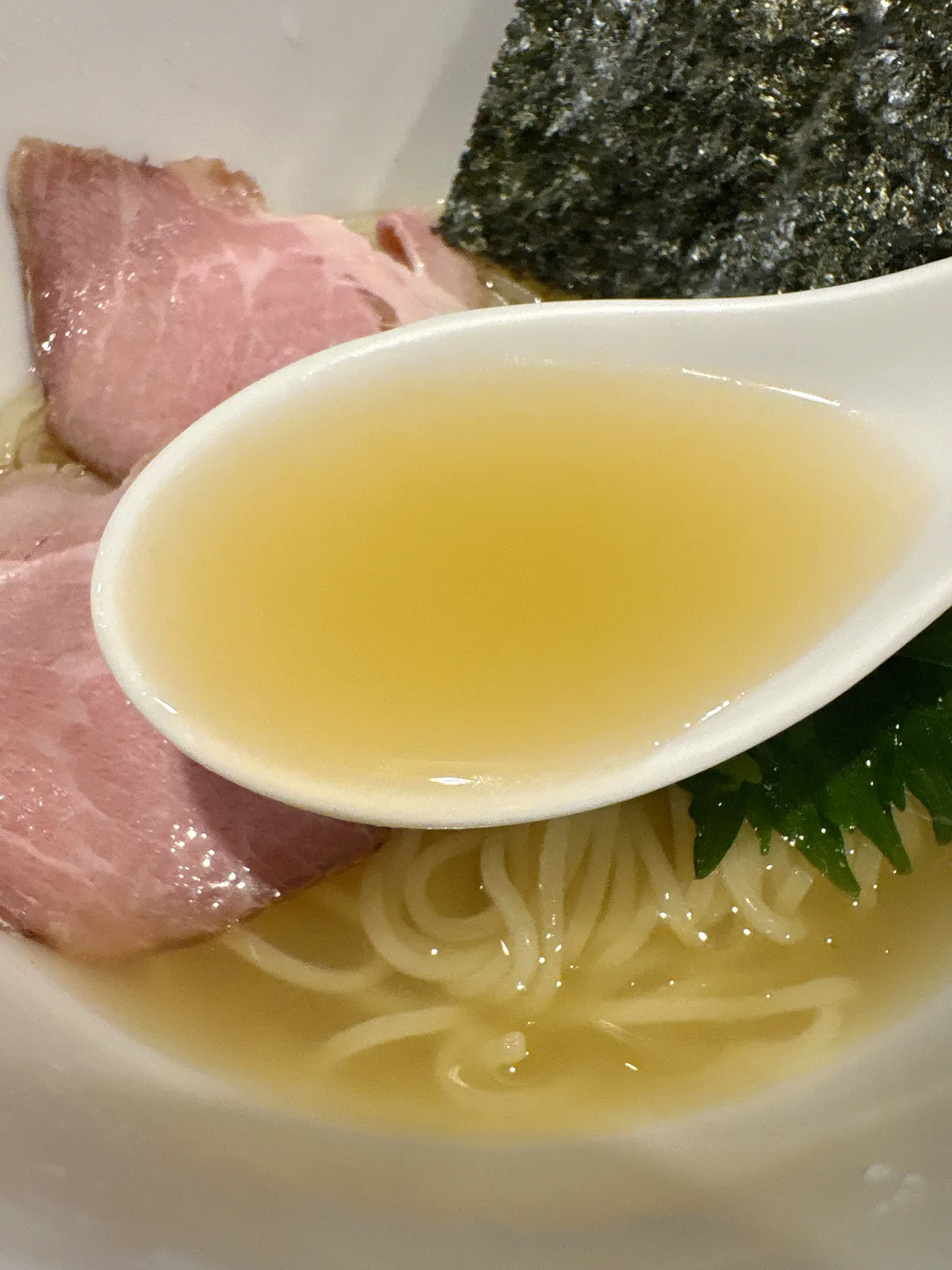ありがた屋の冷製ホタテだしのしおらぅめんのスープをレンゲですくったところ