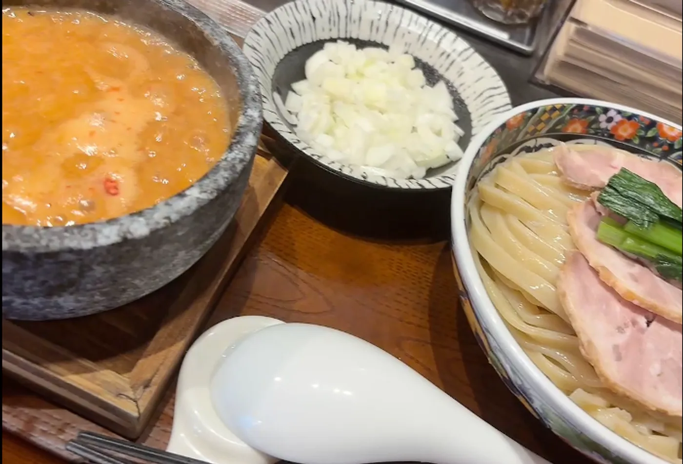 中華蕎麦 一番舎の赤海老つけ麺。石鍋に入った赤いつけ汁と、平打ち麺・チャーシューがのった麺皿