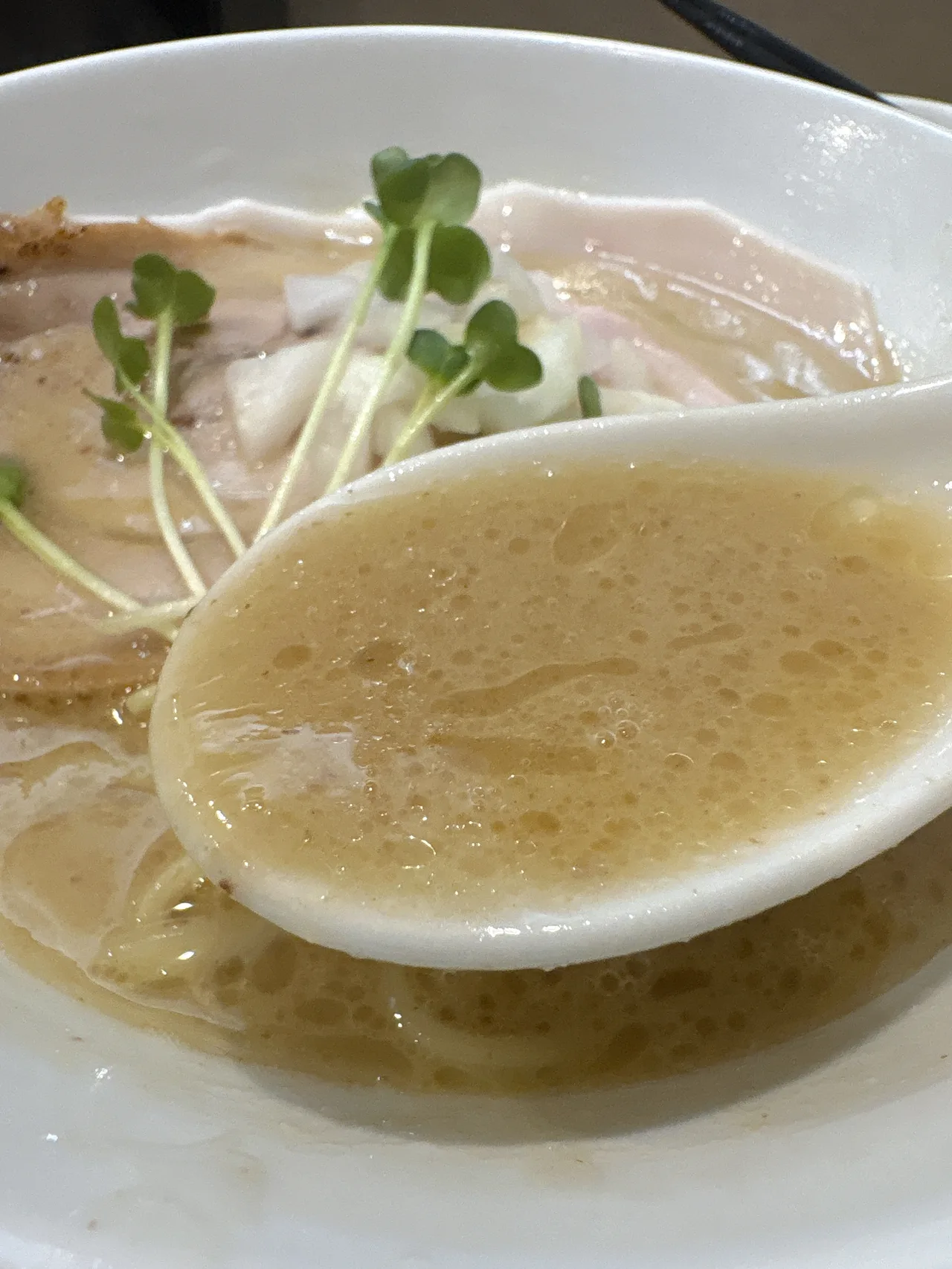 麺屋 伊藤の鳥白湯白醤油らーめんのスープをレンゲですくったところ