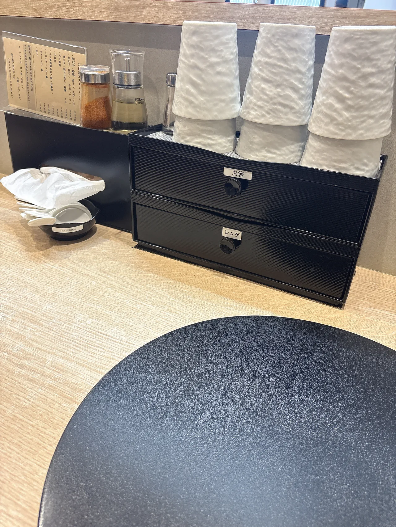 麺屋 伊藤の卓上調味料。唐辛子とお酢のボトルが置かれている