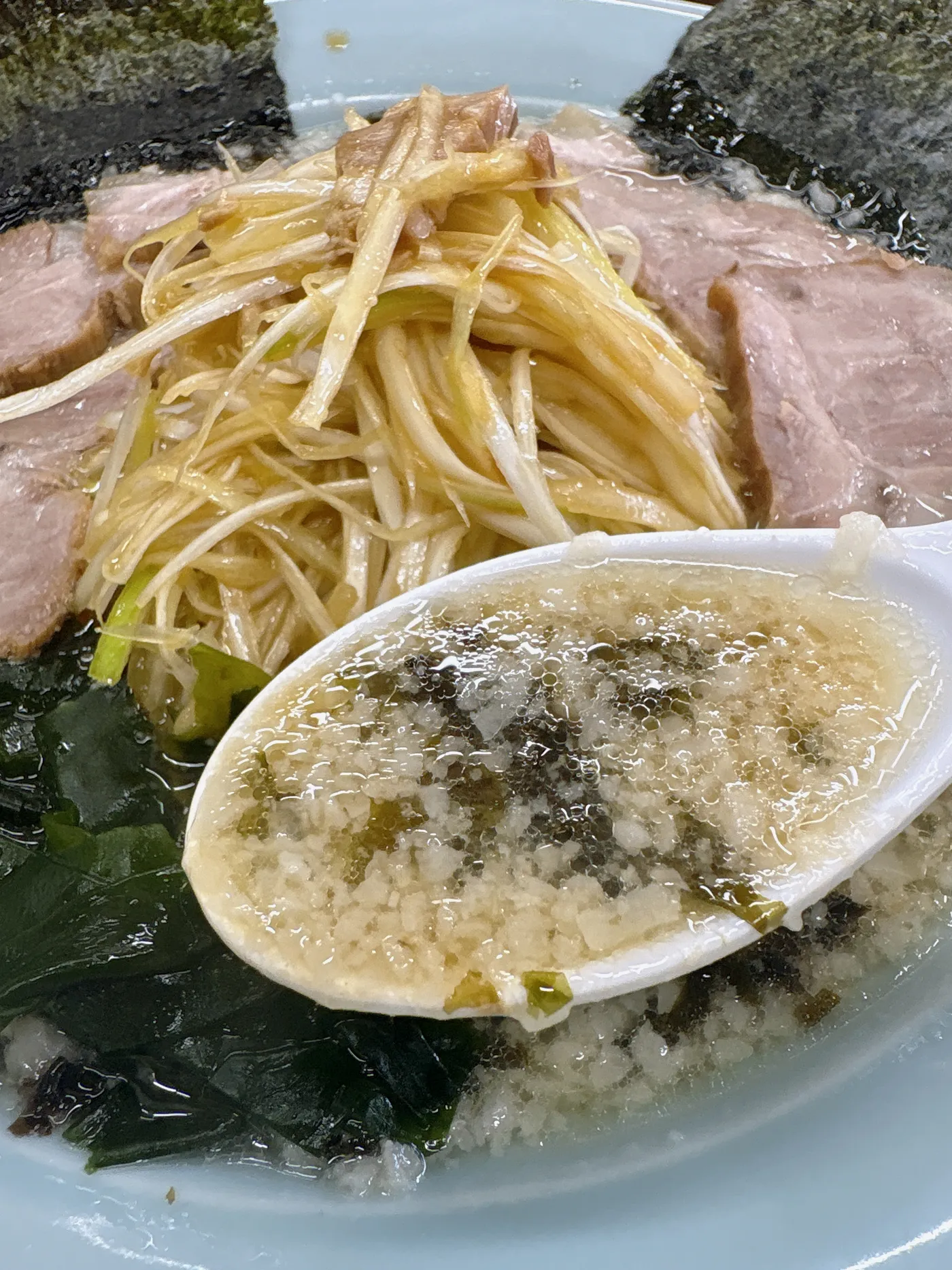 ラーメンショップ春日井店のスープをレンゲですくったところ。背脂が浮いた豚骨醤油スープ