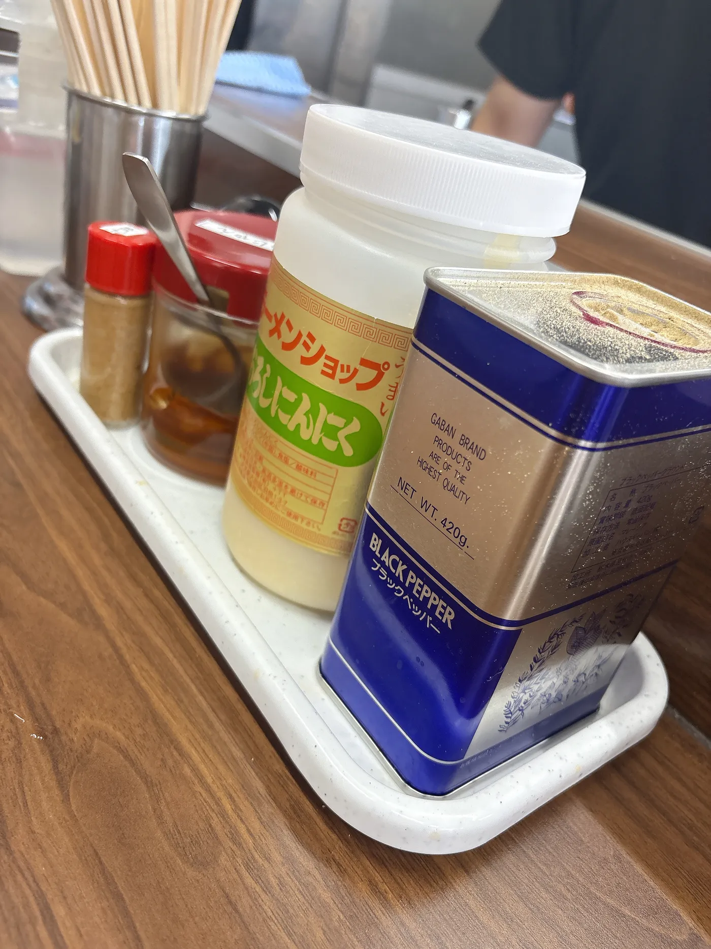 ラーメンショップ春日井店の卓上調味料。おろしにんにくと黒胡椒、辛味調味料が並ぶ