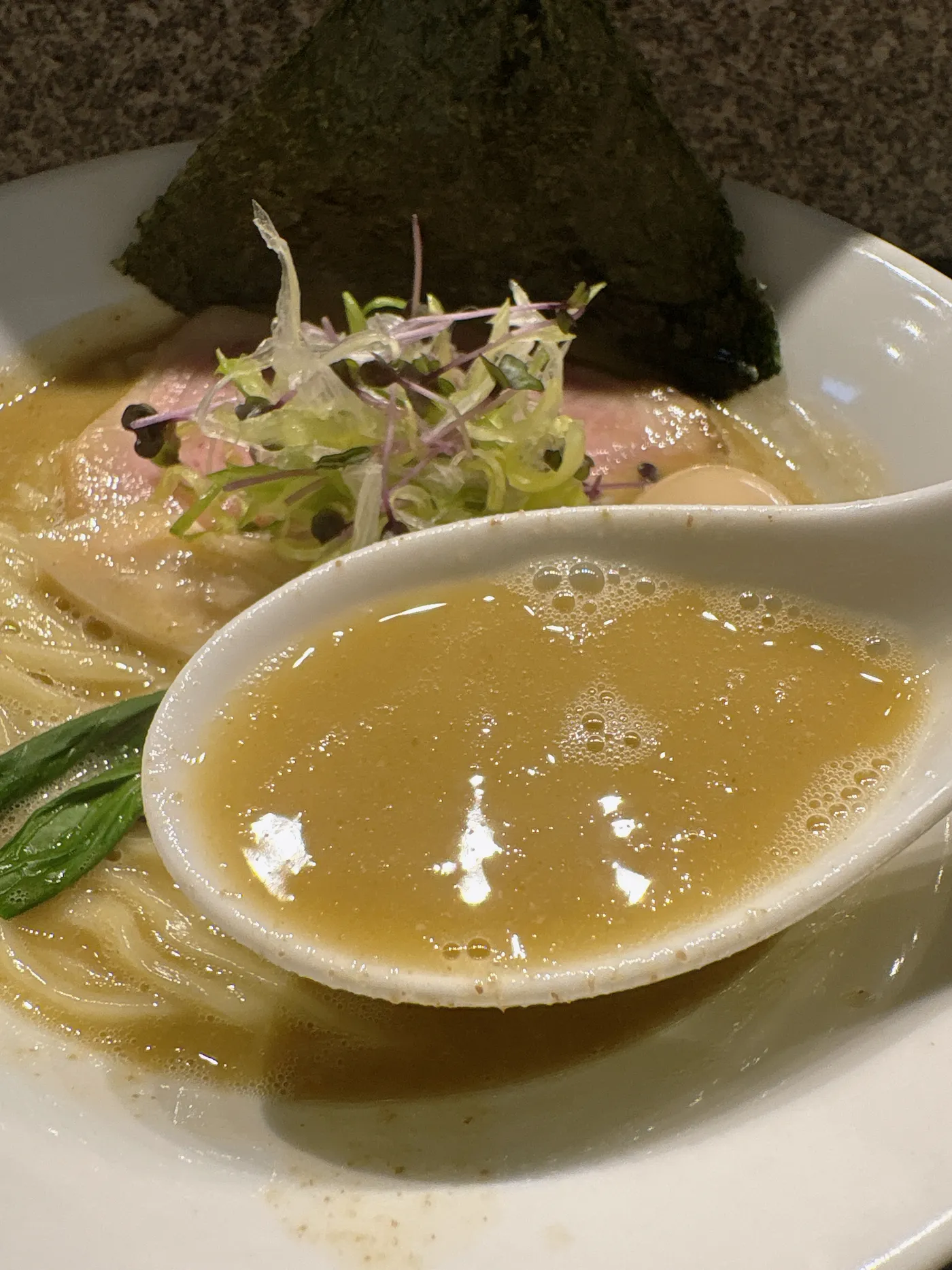 らぁ麺 飛鶏のスープをレンゲですくったところ
