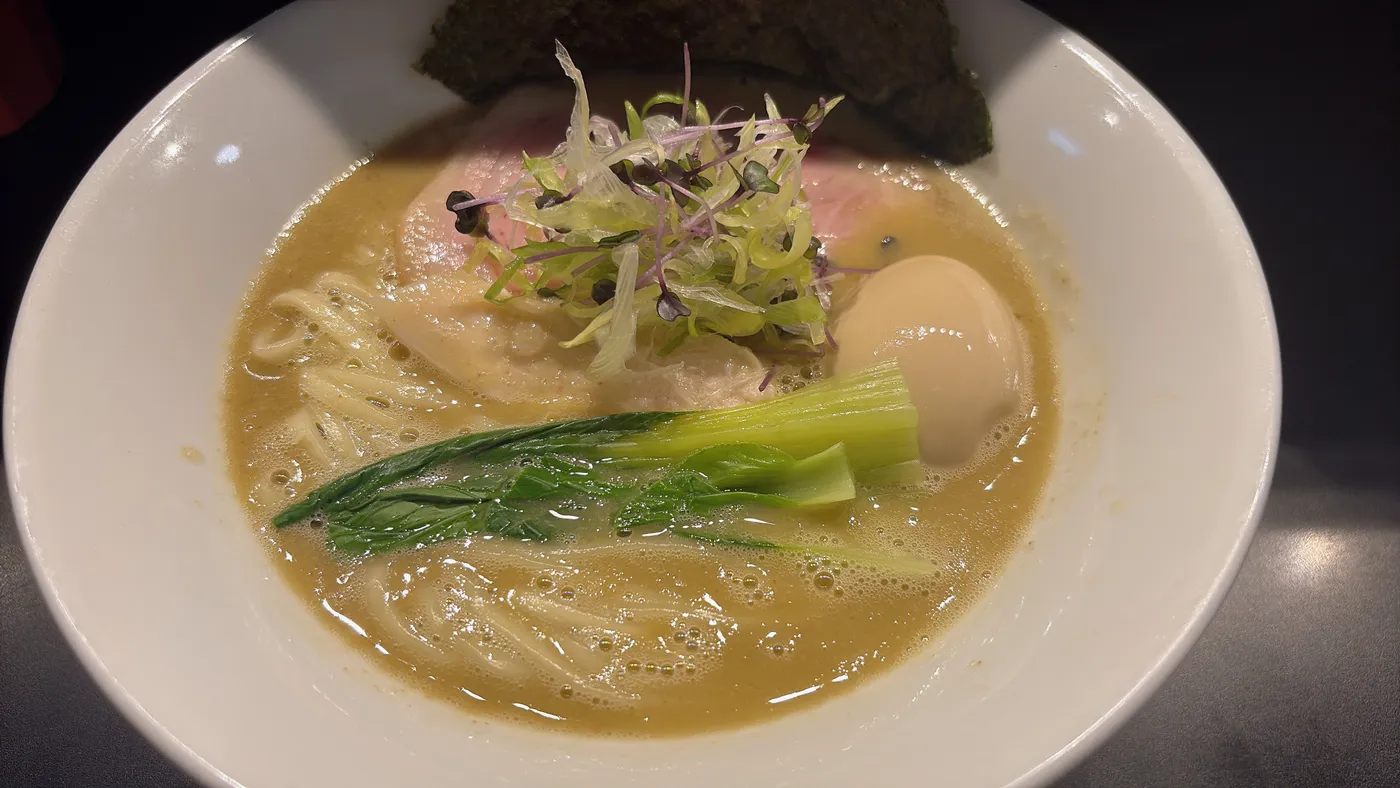 らぁ麺 飛鶏の地鶏の白湯そば。豚チャーシュー、鶏チャーシュー、味玉、九条ネギがのった一杯