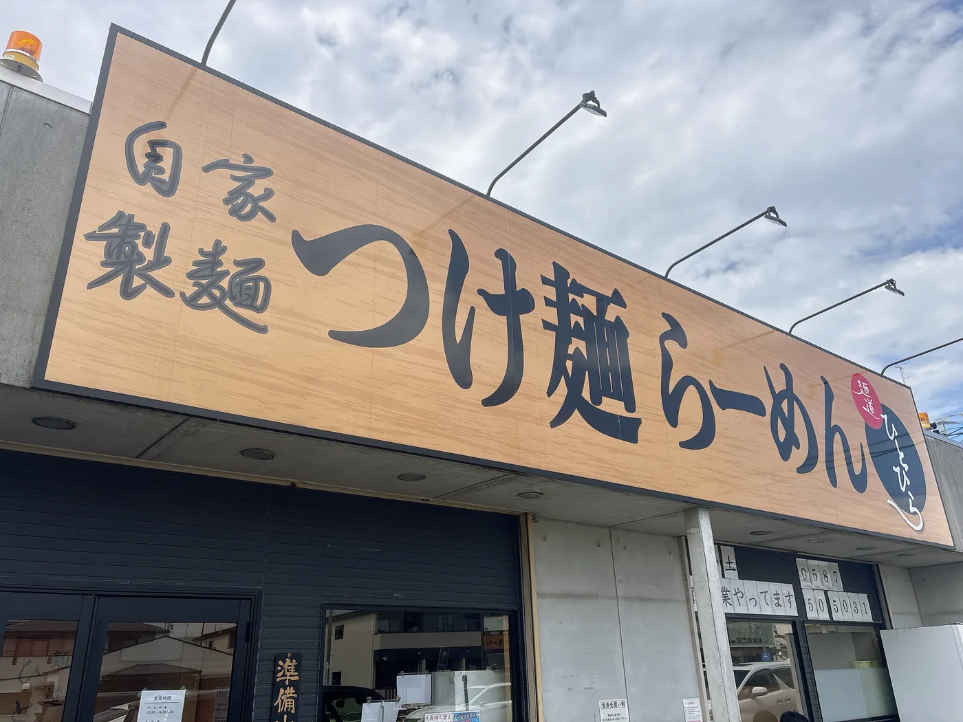 麺道ひとひらの外観。自家製製麺つけ麺らーめんの看板と店先の駐車場