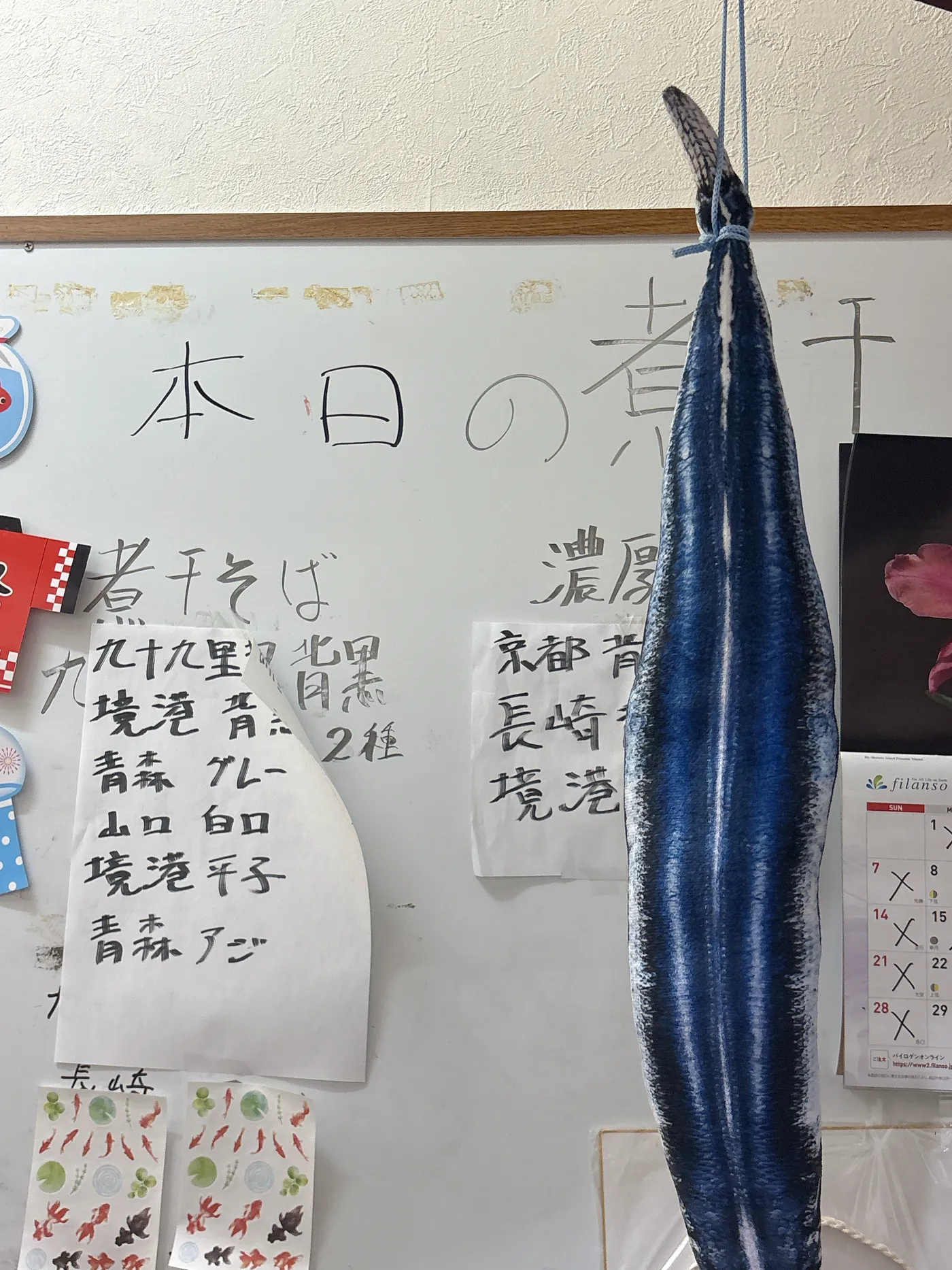煮干し中華そば 魚魚の店内。本日の煮干しの産地を書いたホワイトボードと、天井から吊るされた大きな煮干し