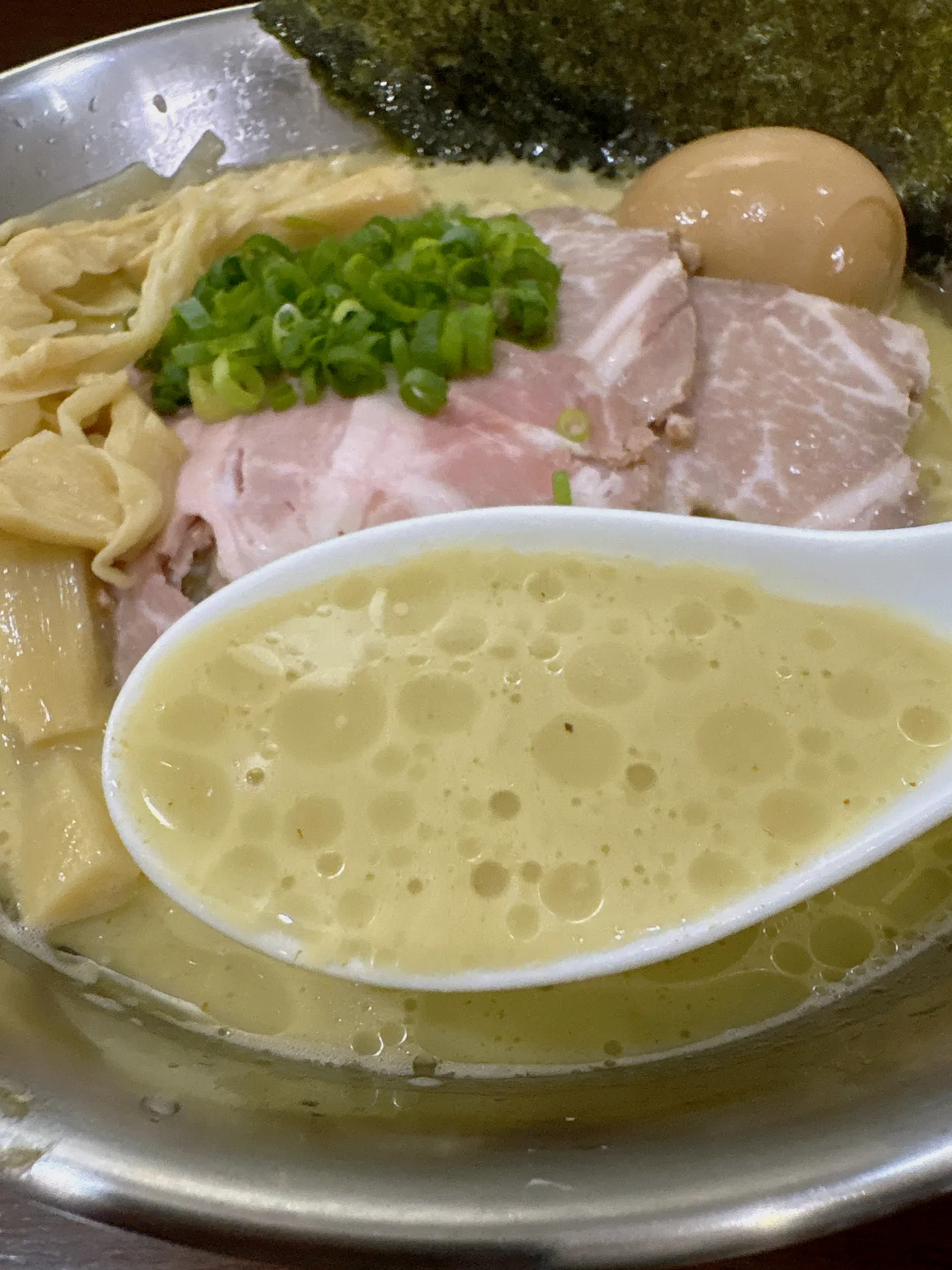 煮干し中華そば 魚魚の冷やかきのスープをレンゲですくったところ