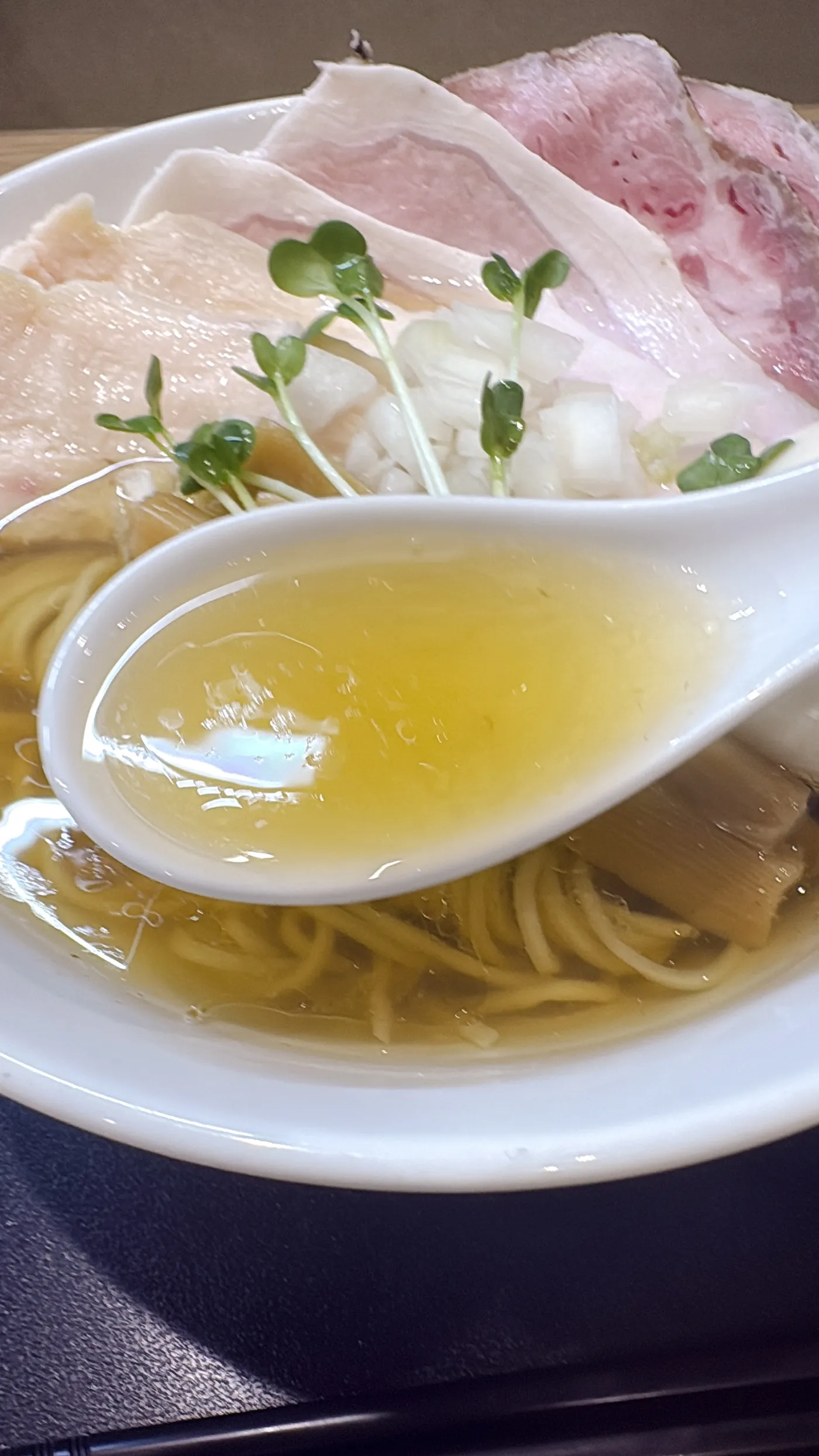 麺屋 伊藤の特製白醤油らーめんのスープをレンゲですくったところ