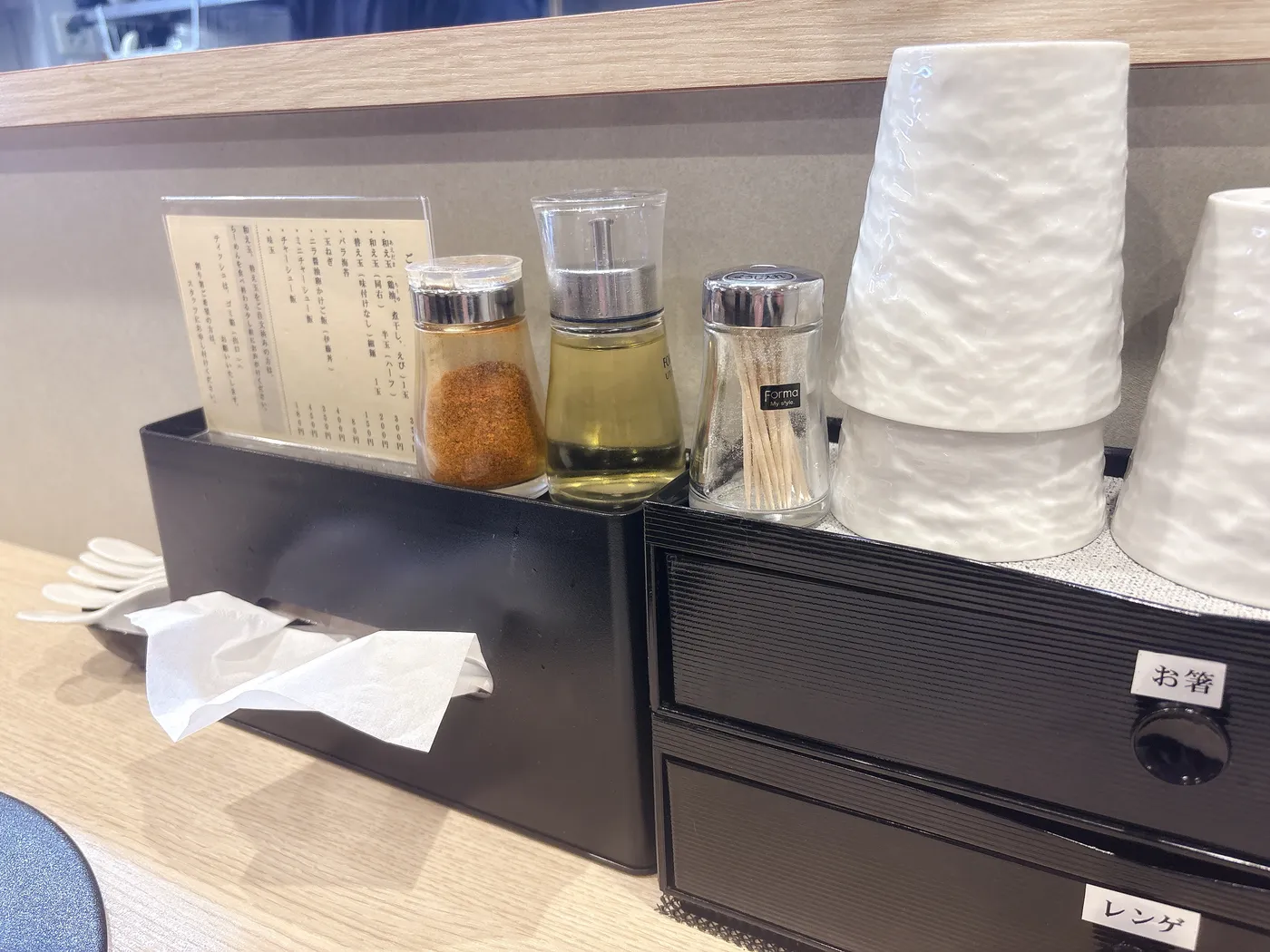 麺屋 伊藤の卓上。一味唐辛子や香味油、爪楊枝などが並ぶ