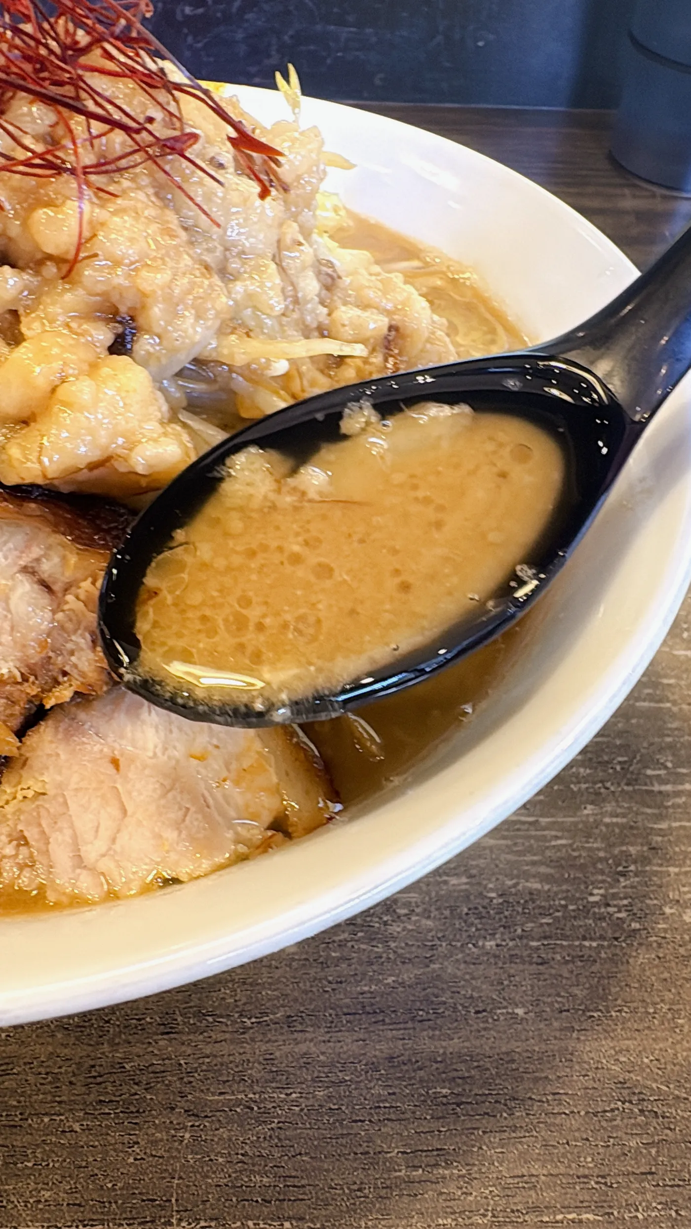 ラーメンつづきのスープをレンゲですくったところ。しっかり乳化した色合い