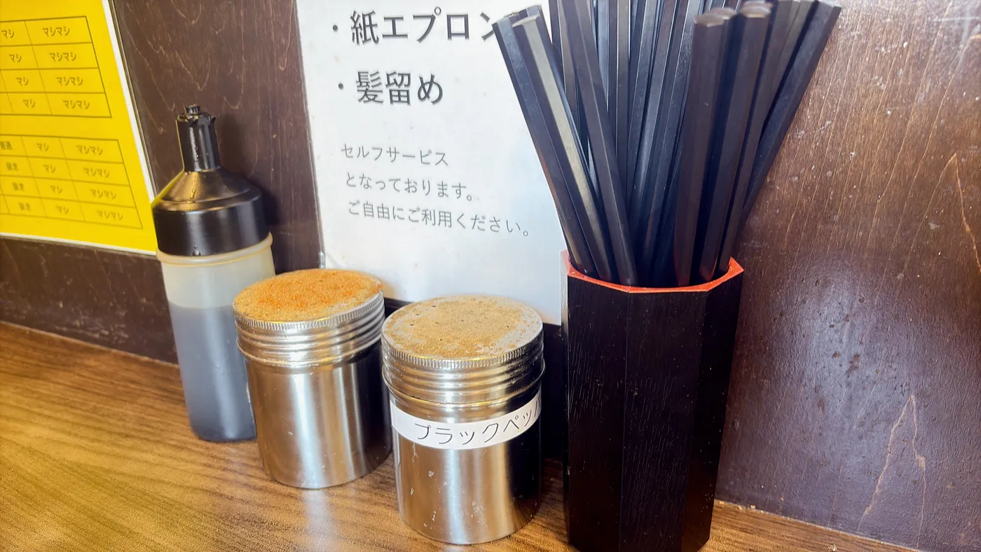 ラーメンつづきの卓上調味料。カエシ、一味唐辛子、ブラックペッパーが並ぶ