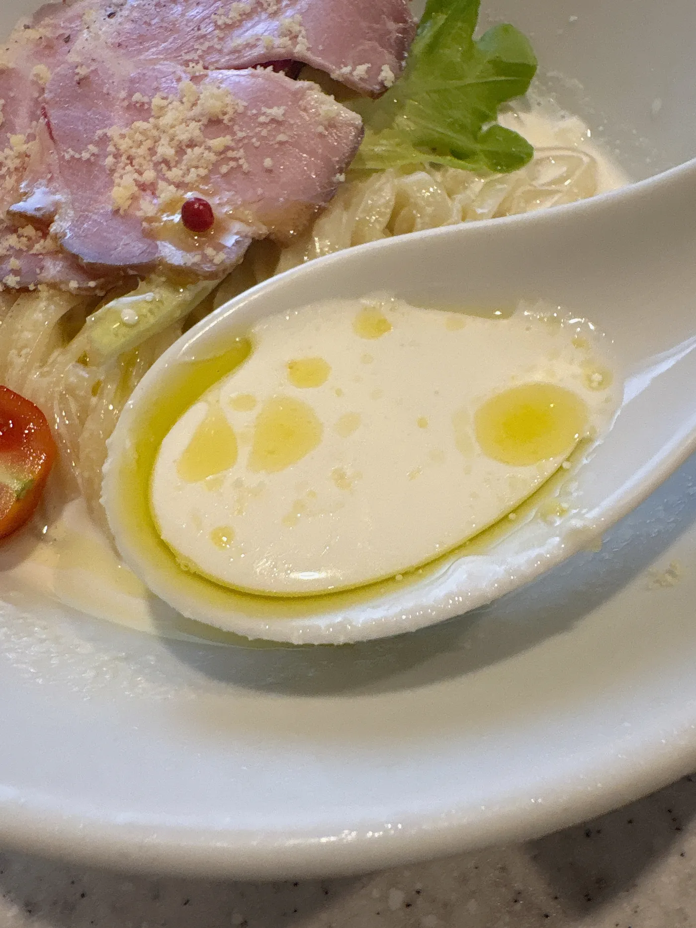 らぅめん考房 ありがた屋の冷製フロマージュ和え麺のスープ部分。ミルキーなチーズソースにピンクペッパーが散る