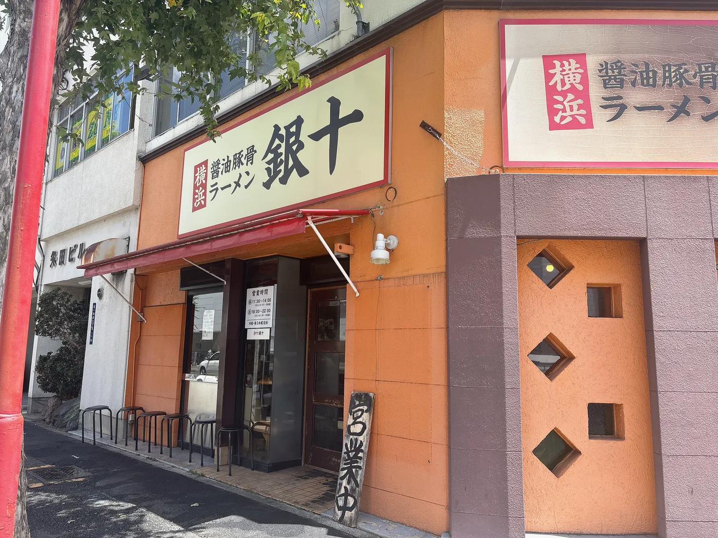 銀十の店構え。「横浜 醤油豚骨ラーメン 銀十」の看板が掲げられたオレンジ色の外観
