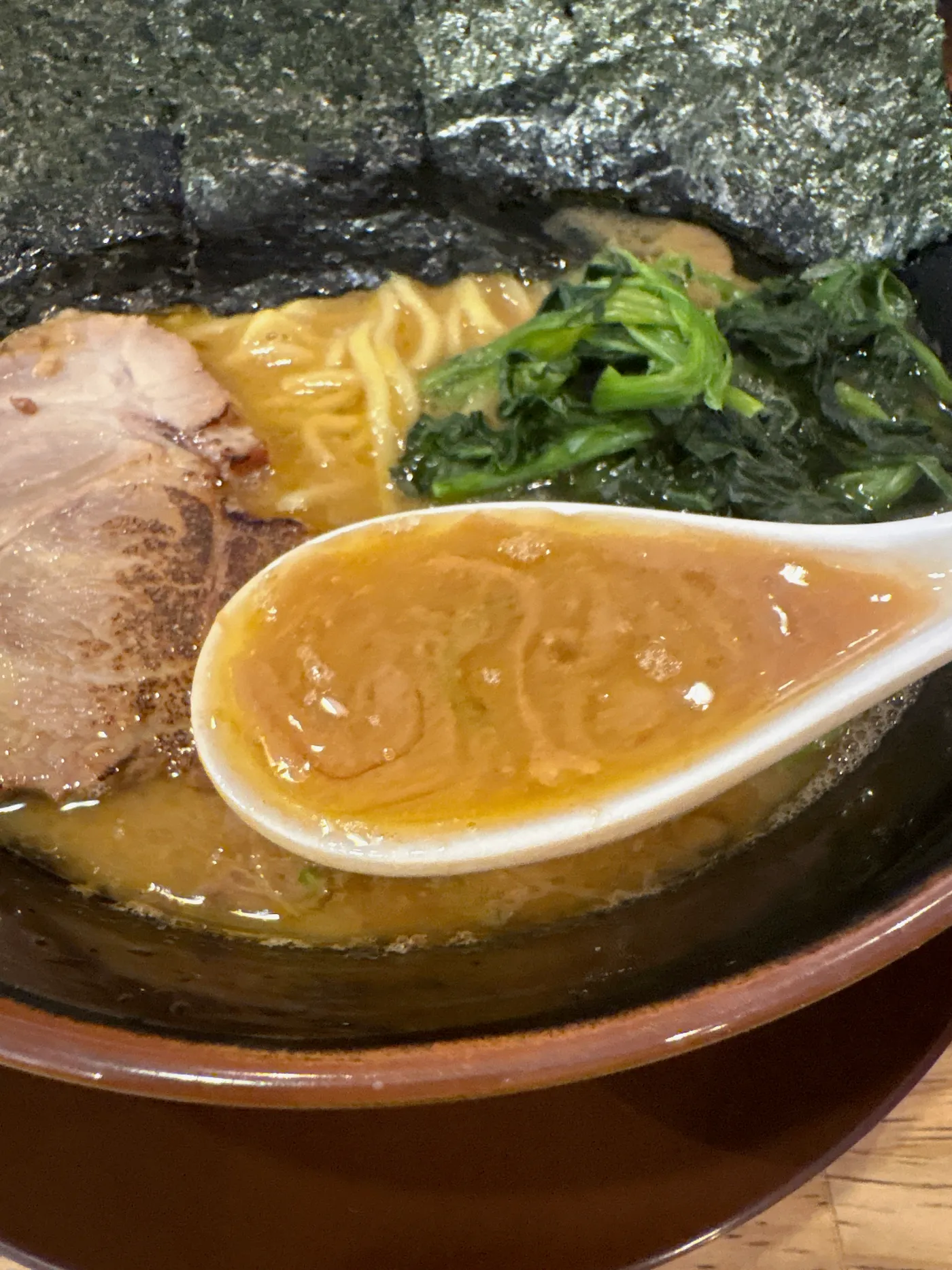 銀十のスープをレンゲですくったところ。明るい茶色でさらりとしている