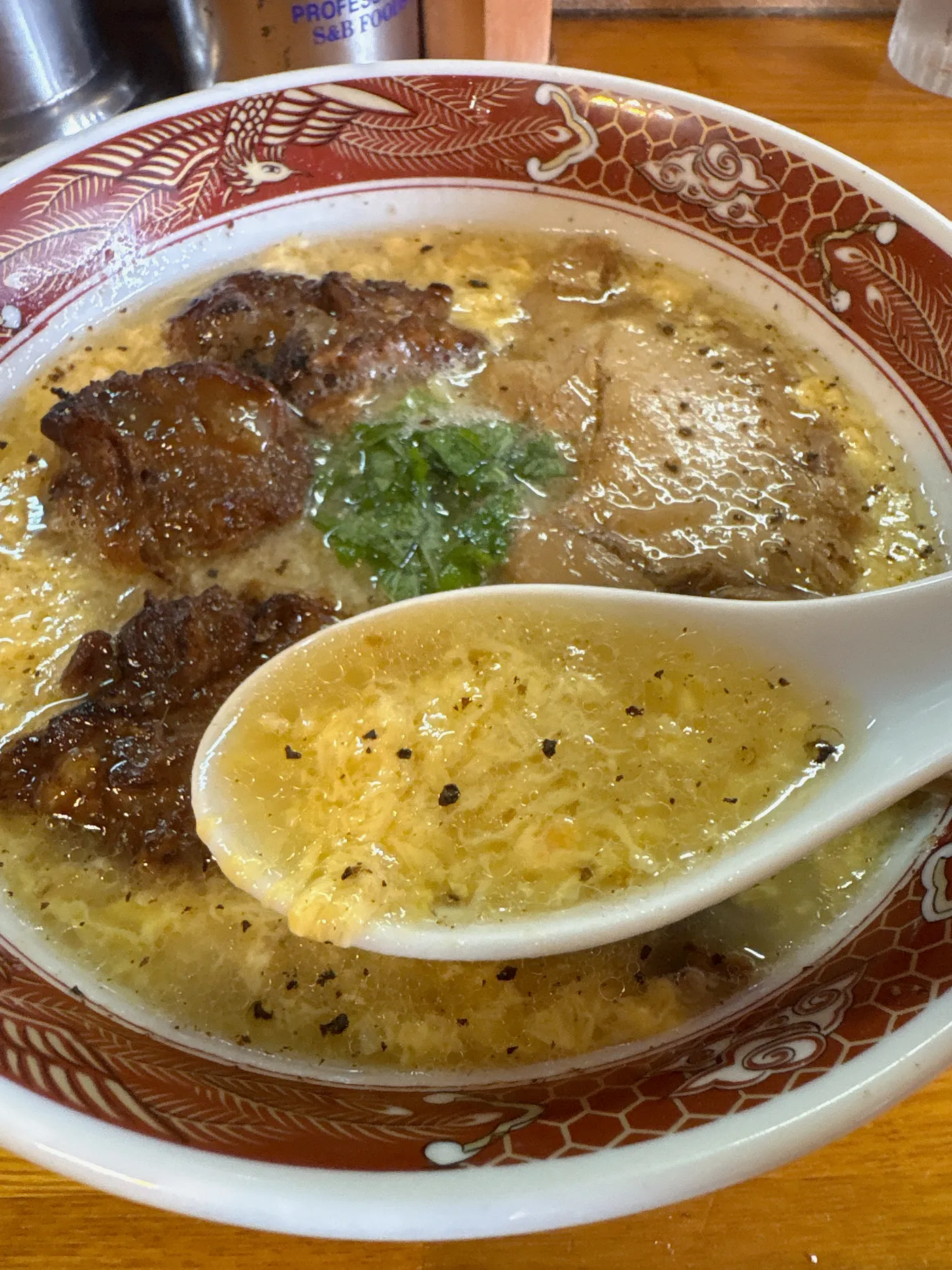 レンゲですくった臺大の塩くもたまスープ。細かくとじられた卵と黒胡椒が浮かぶ