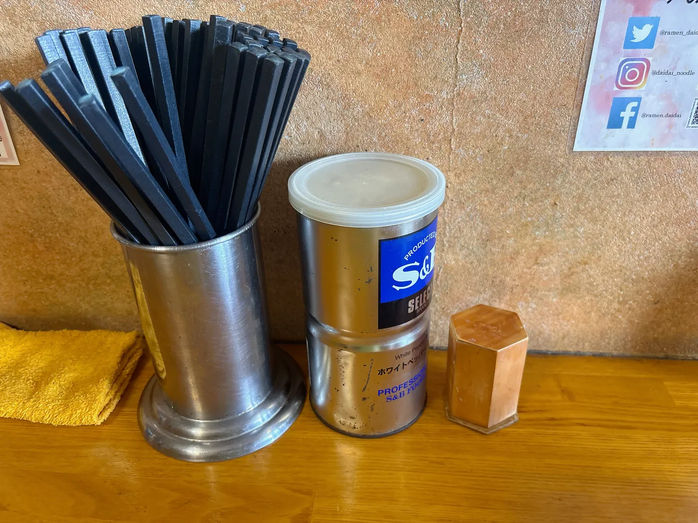 臺大の卓上。箸立てとS&Bのホワイトペッパーの缶が並ぶ