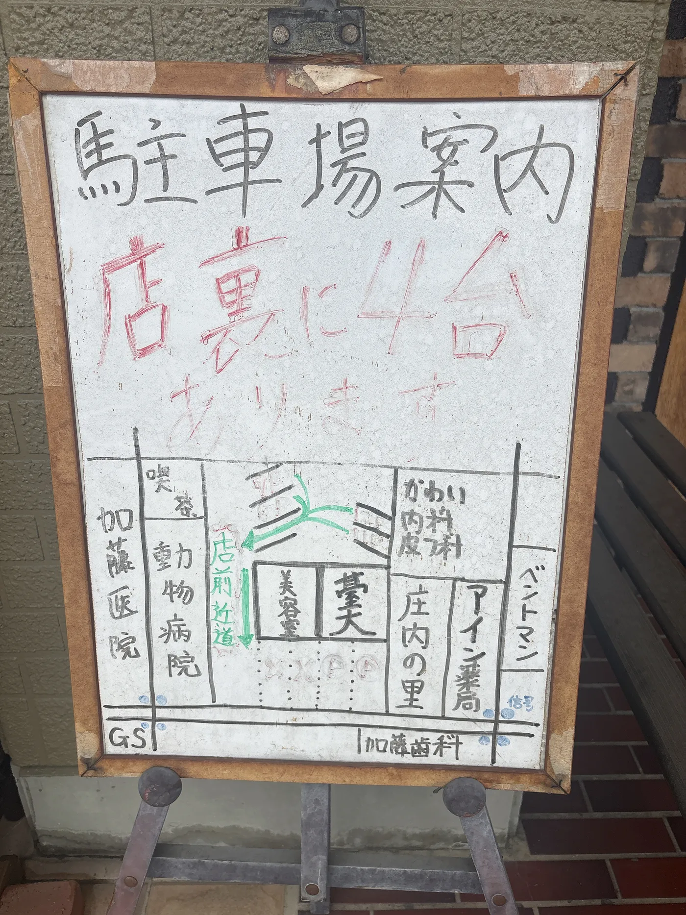 店頭の手書きの駐車場案内板。「店裏に4台あります」と周辺の地図が描かれている