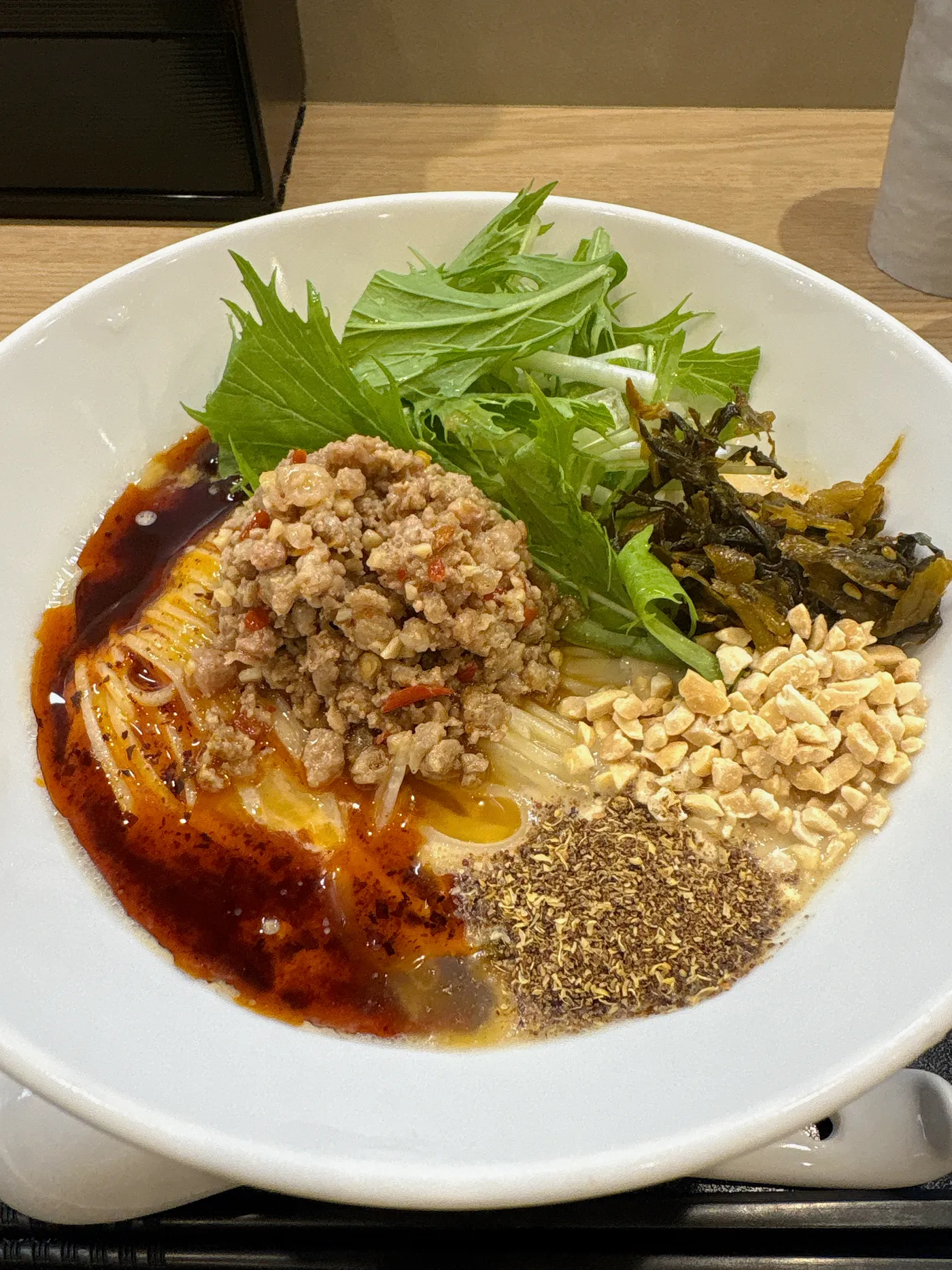 冷やし豆乳担々麺のトッピング。ミンチ、砕いたナッツ、山椒、水菜が丼の中に彩りよく並ぶ