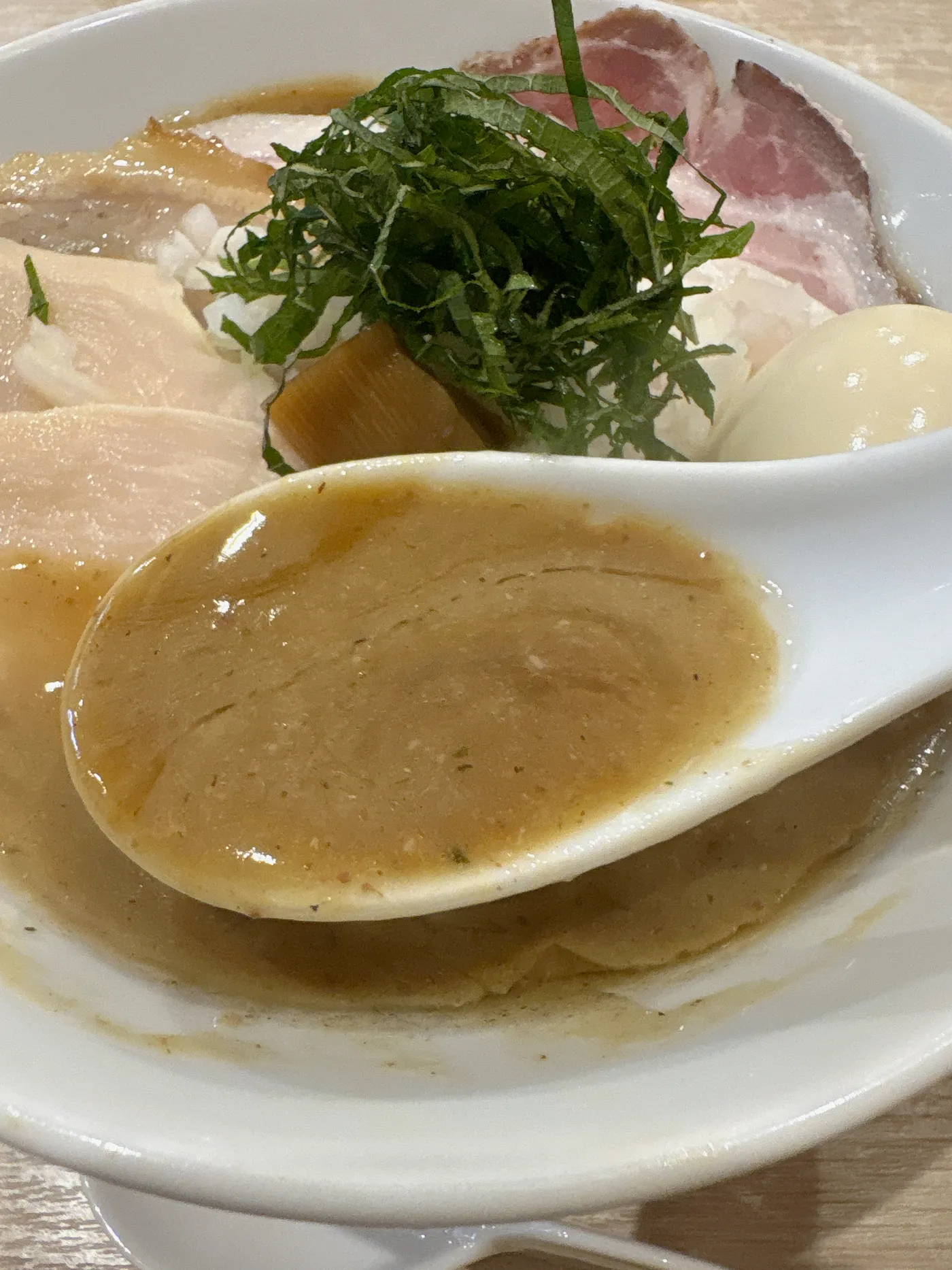 レンゲですくった麺屋 伊藤の鶏白湯醤油スープ。とろみのある濃厚なスープがレンゲにたっぷり残る
