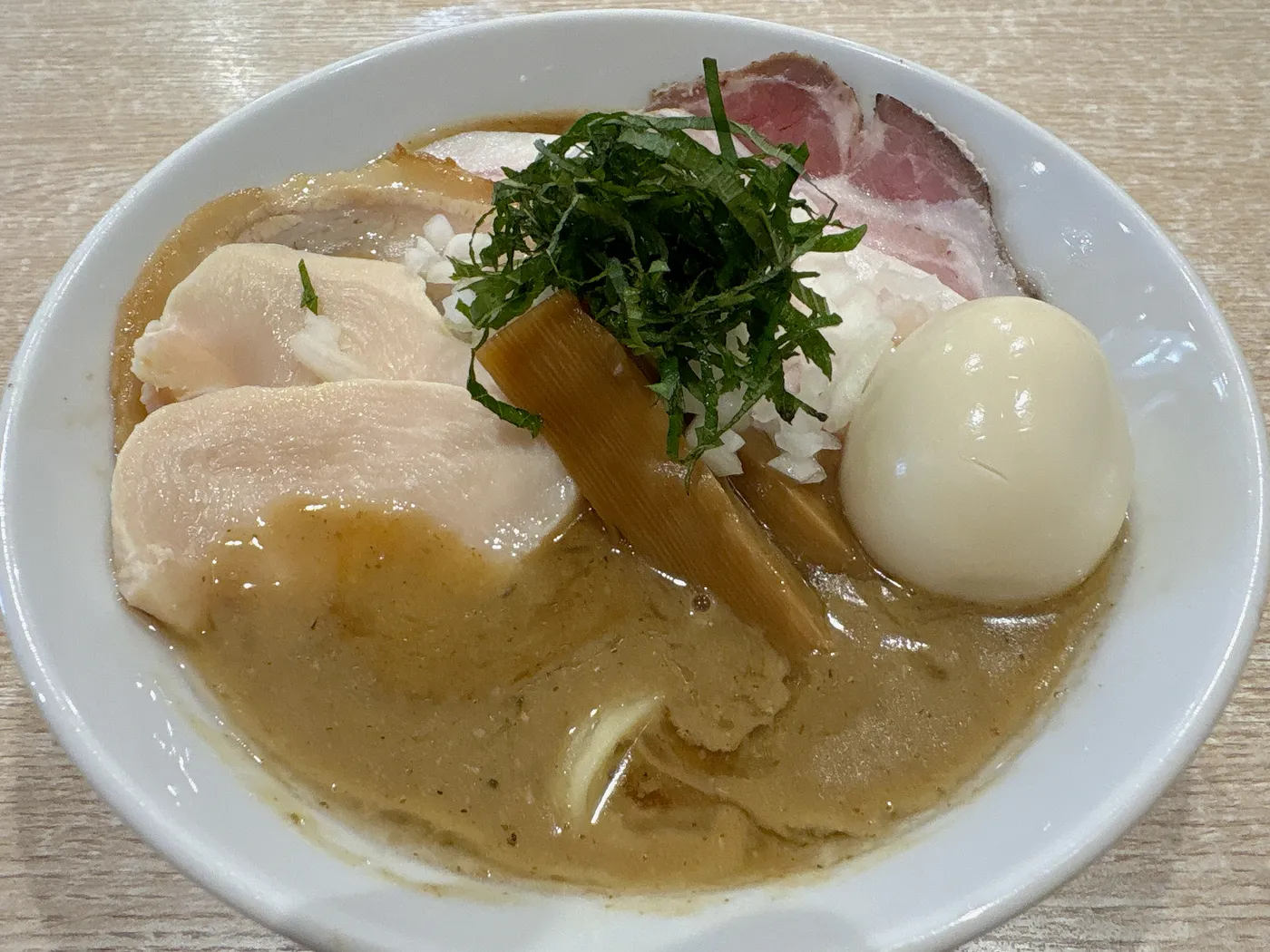 麺屋 伊藤の特製鶏白湯醤油ラーメン。とろみのある濃厚なスープに鶏チャーシュー、レアチャーシュー、味玉、メンマ、大葉の千切りがのる